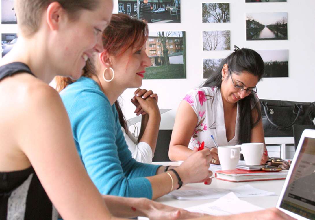 drei Frauen am Arbeitstisch mit Papier und Laptop