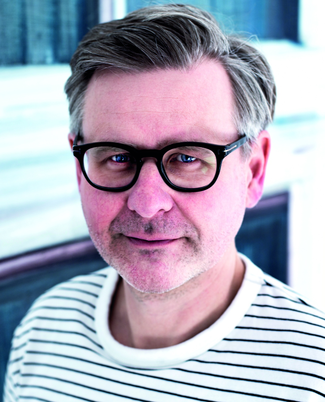 Porträtfoto Martin Simons, grauhaariger Mann mit prägnanter schwarzer Brille im gestreiften Shirt