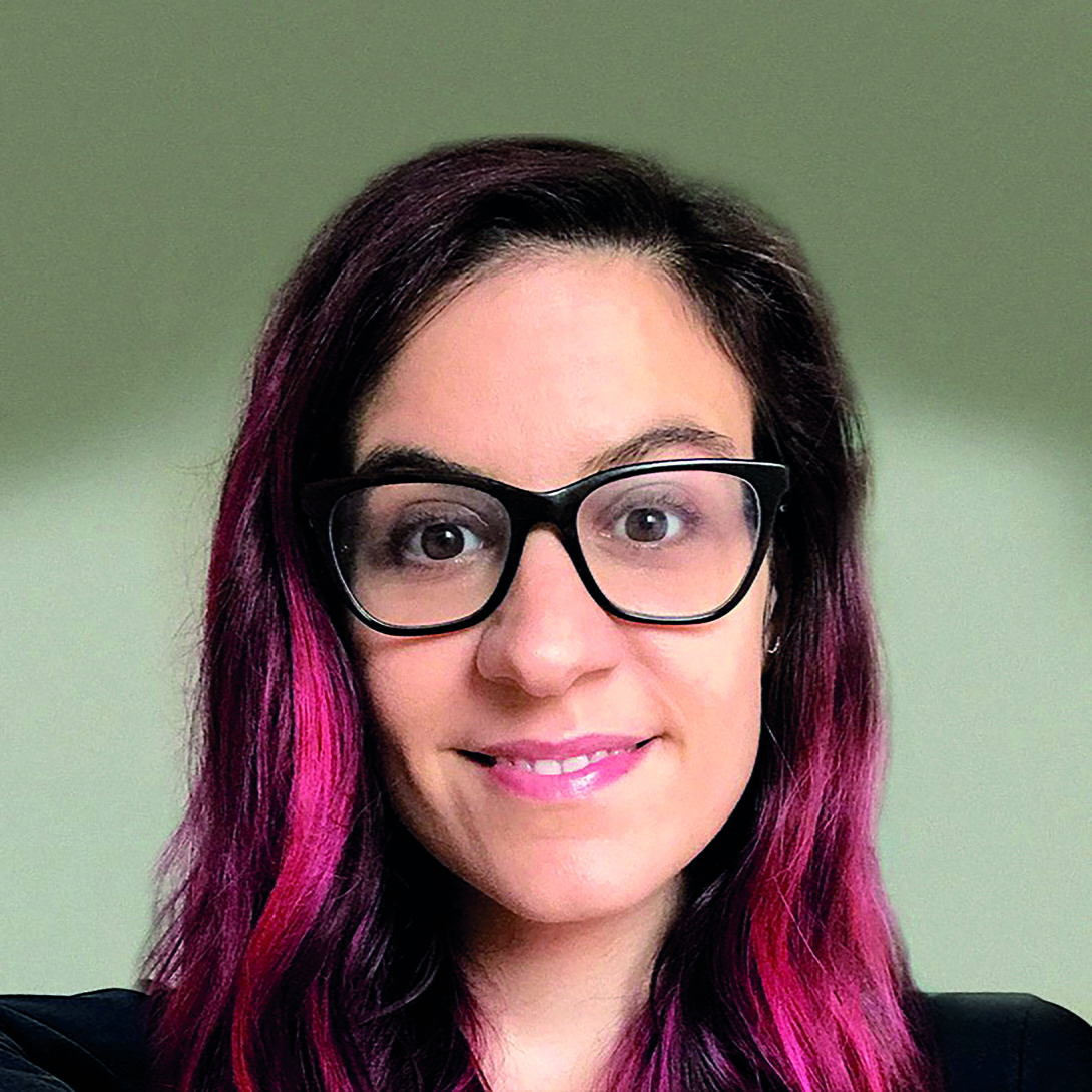 Frau mit langen dunklen Haaren mit pinken Strähnen und einer großen schwarzen Brille