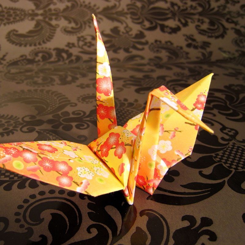Vogel aus Origami, gelbes Papier mit roten Blumen