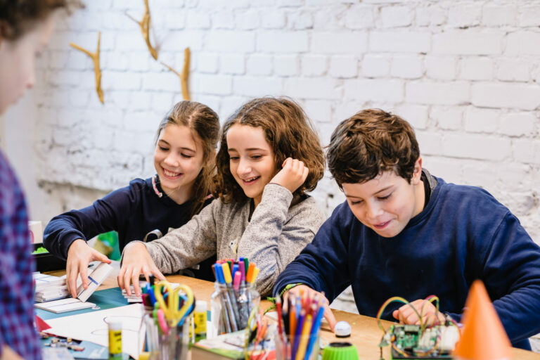 drei Kinder bastelnd am Tisch mit verschiedenen Materialien