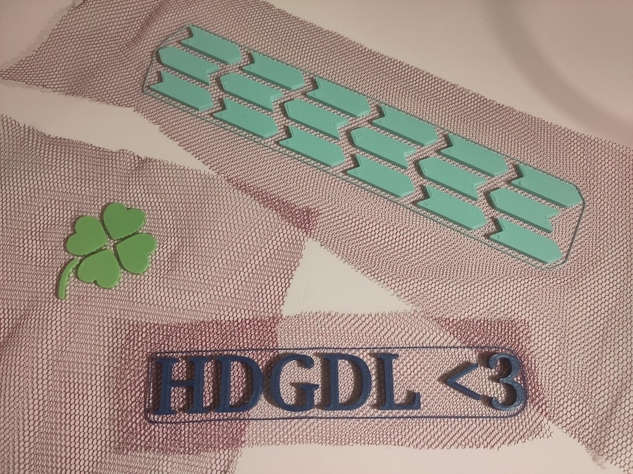 kleine Muster, Buchstaben, eins wie Autoreifenprofil, ein kleines Kleeblatt aus dem 3-D-Drucker auf Stoff