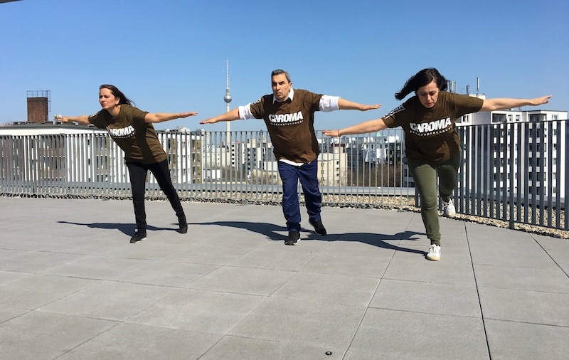 drei Personen auf dem Dach des Aufbau Haus in einer Pose, als würden sie fliegen wollen