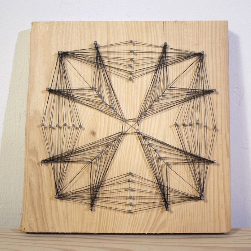 String Art Kunstwerk, eine Holzplatte, auf der Fäden so um Nägel gespannt sind, dass sich ein eckiges, sternartiges Muster ergibt