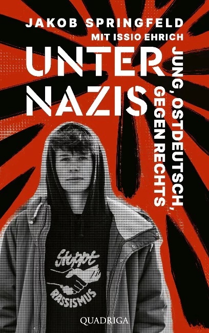 Buchcover, junger Mann mit grauer Kapuzenjacke vor schwarz-rotem Hintergrund, darüber in weißen Lettern der Titel "Unter Nazis", außerdem Autorenangabe und Untertitel: Jakob Springfeld mit Issio Ehrich; Jung, ostdeutsch, gegen rechts