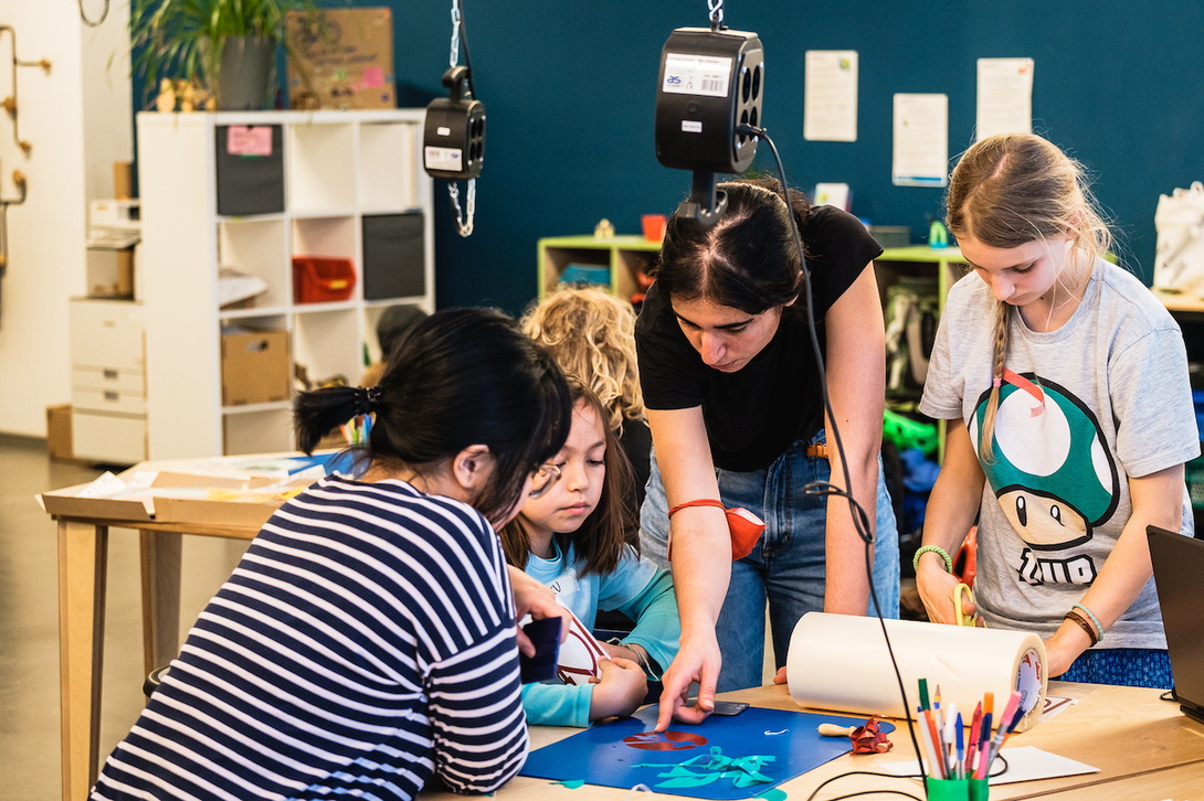 Gruppe von Kindern und Jugendlichen beugt sich über ein gemeinsames Projekt auf einem Tisch
