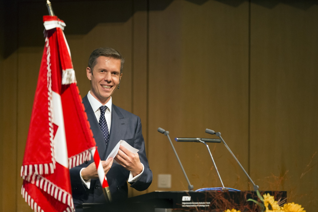 mittelalter weißer Mann im Anzug hinter einem Rednerpult neben einer großen roten Fahne, die herunterhängt