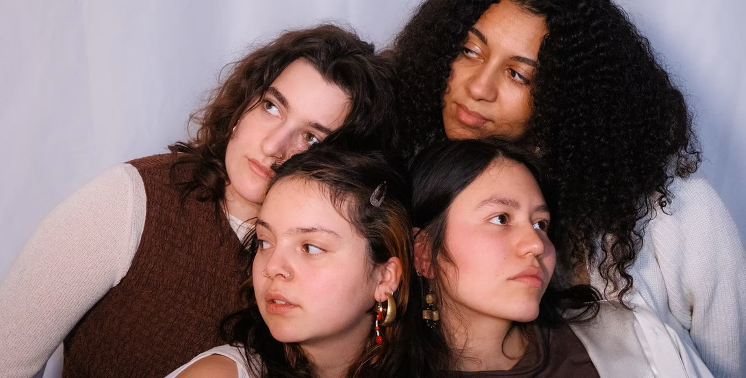 Nahaufnahme von den Köpfen von vier jungen, langhaarigen Frauen 