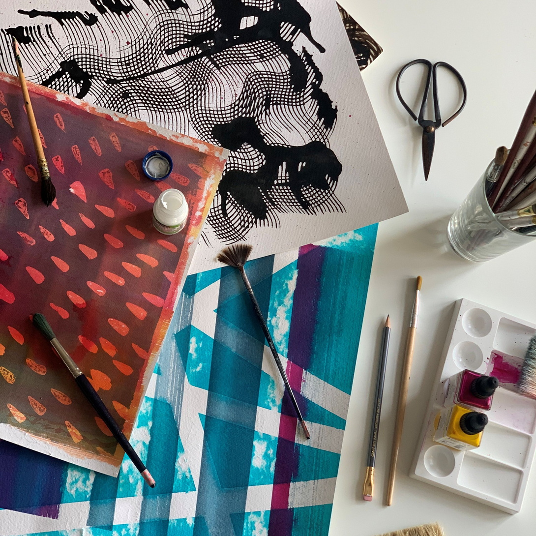 Tisch voller Bastelmaterialien, von oben aufgenommen, verschiedene Arten von Papier, Schere, Pinsel etc.