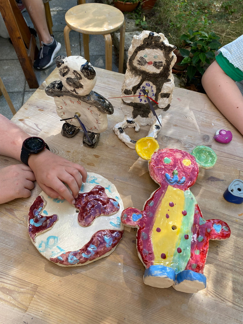 bunt glasierte Ton-Objekte mit weißen Kinderhänden