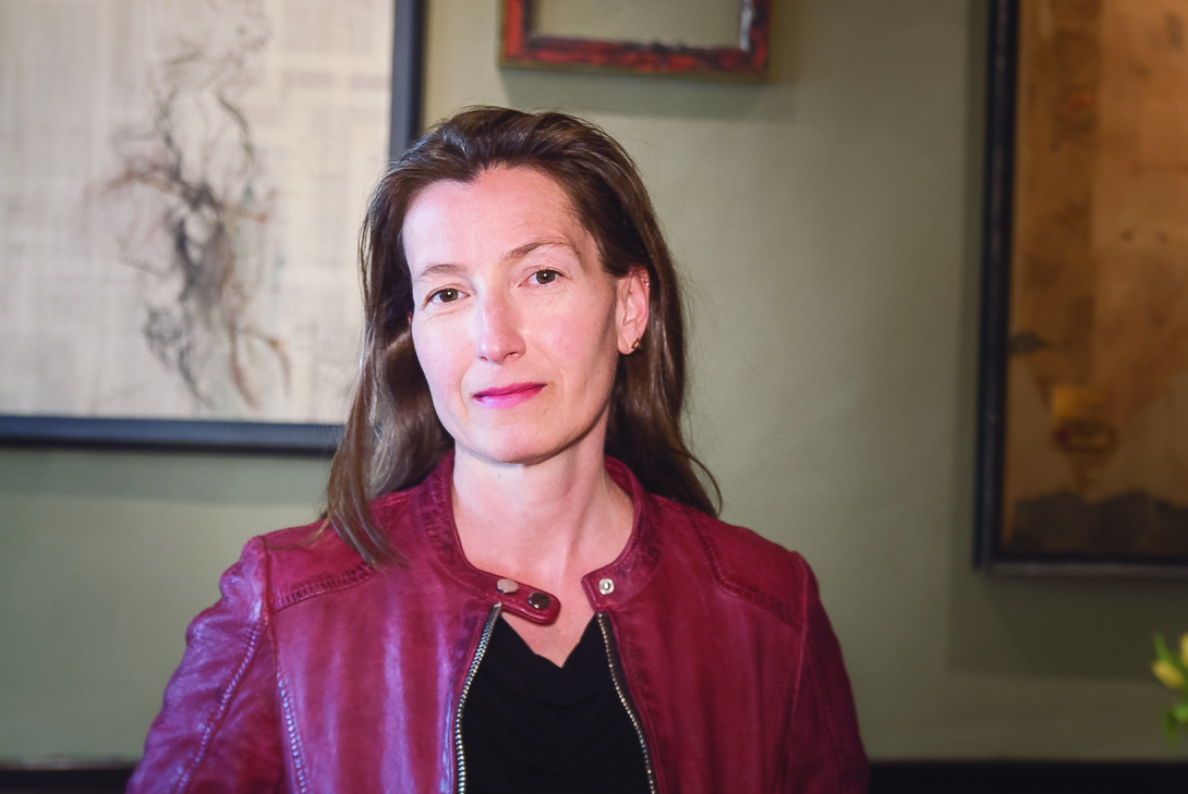 mittelalte Frau mit langen braunen Haaren in weinroter Lederjacke