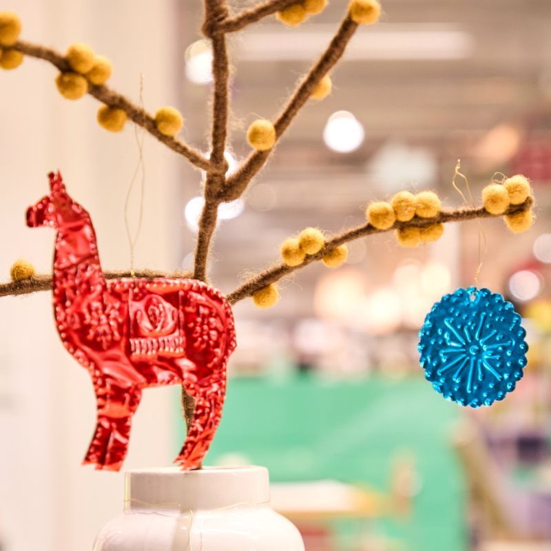 Ein selbstgebauter Ast in einer Vase. An ihm hängt ein rotes Rentier und eine blauer Schneekristall.