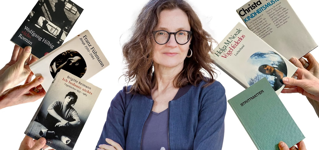 Eine Frau mit schulterlangem braunem Haar und Brille steht mit verschränkten Armen vor weißem Hintergrund. Um sie herum halten mehrere Hände Bücher bekannter DDR-Autorinnen und -Autoren hoch.