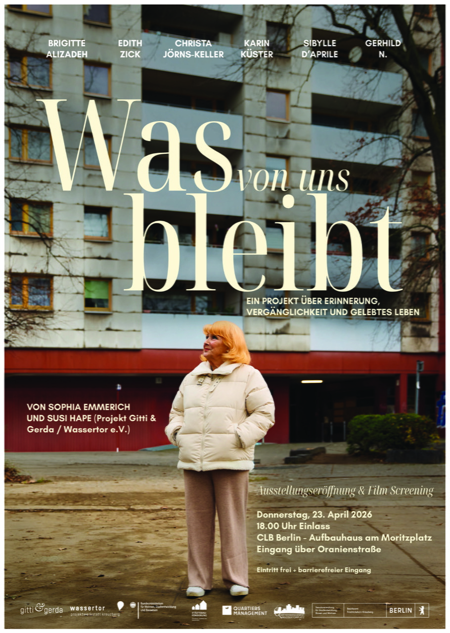 eine ältere Frau in einer beigen Daunenjacke und einer hellbraunen Hose steht entspannt vor einem Hochhaus und schaut in die Ferne